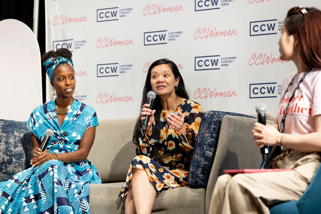 Three women sit on a stage holding microphones, engaged in a panel discussion at a Customer Contact Week event.