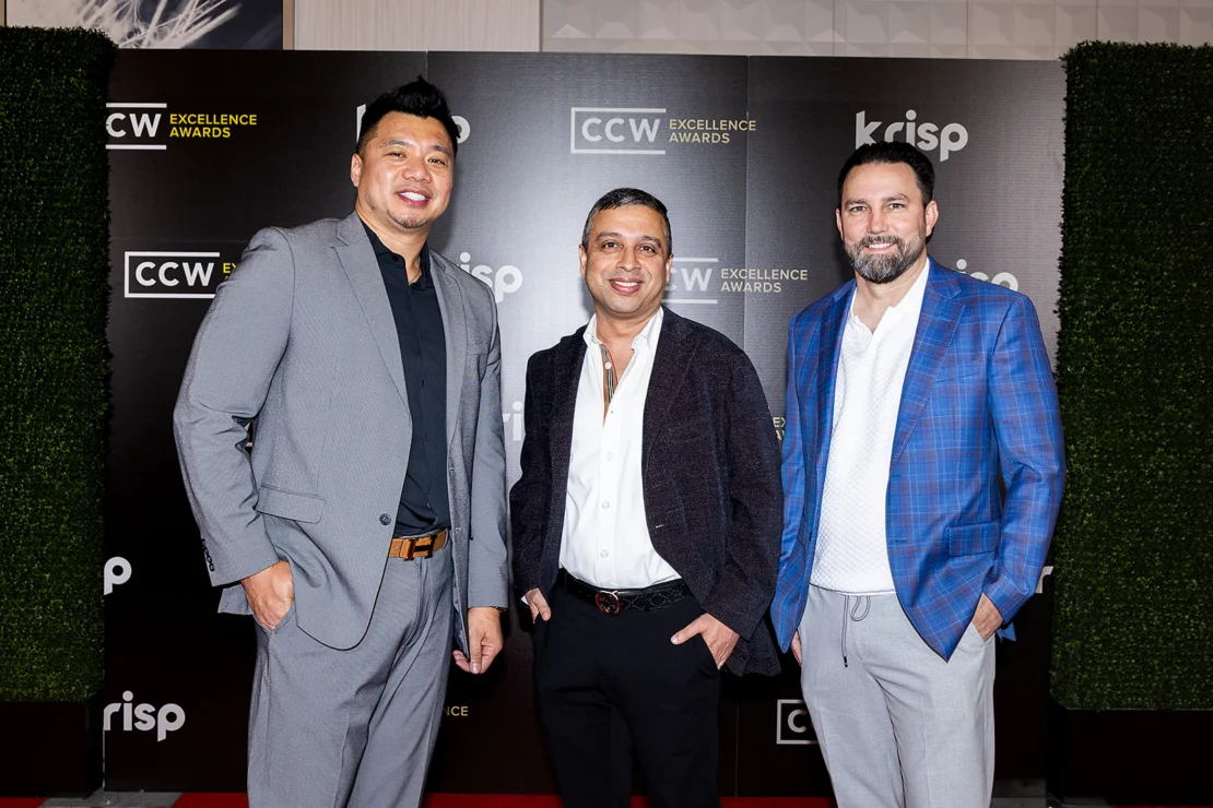 Three men in suits stand on a red carpet in front of a backdrop with "CCW Excellence Awards" and "krisp" logos.