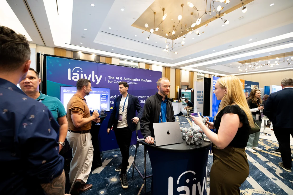 People interact at a Laiyley booth at a conference, with promotional materials, a laptop, and banners about AI and automation in a modern exhibition hall.