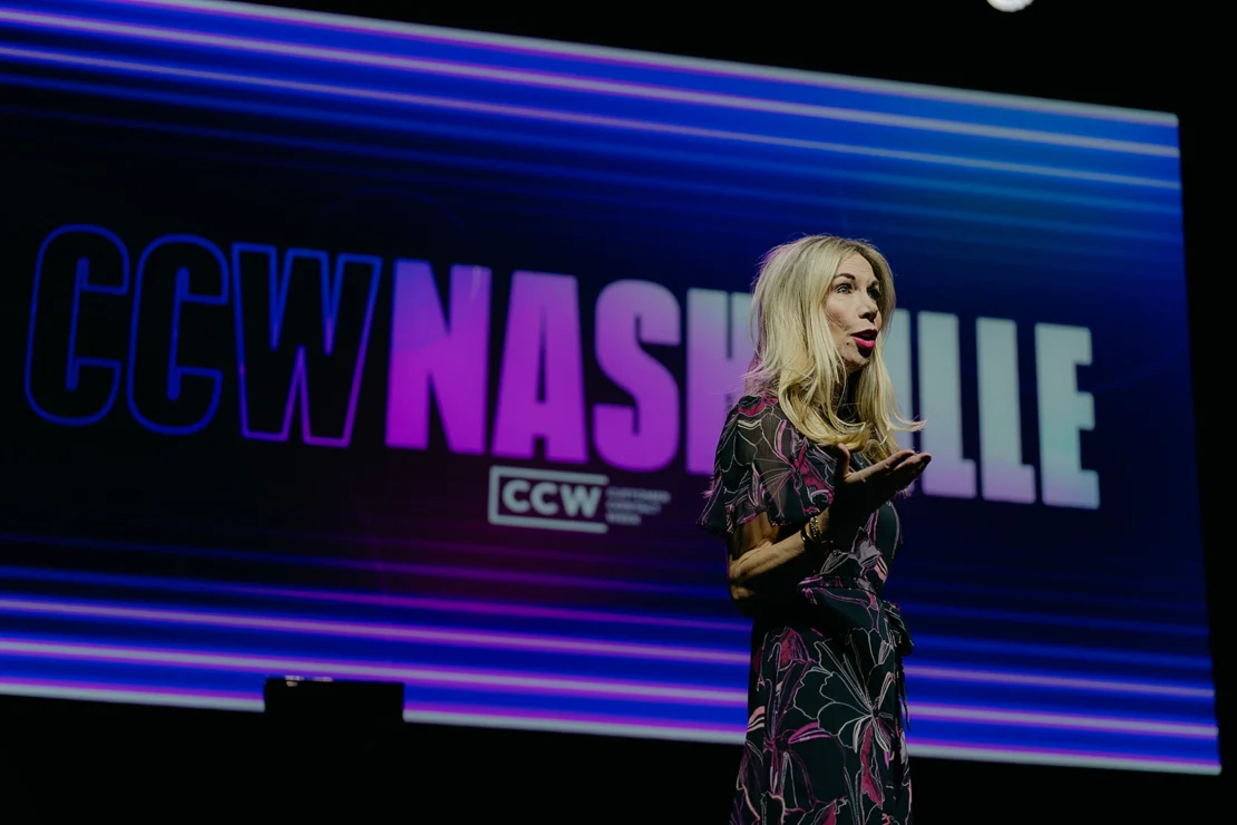 A woman speaks on stage in front of a large screen displaying "CCW NASHVILLE" with purple and blue lighting.