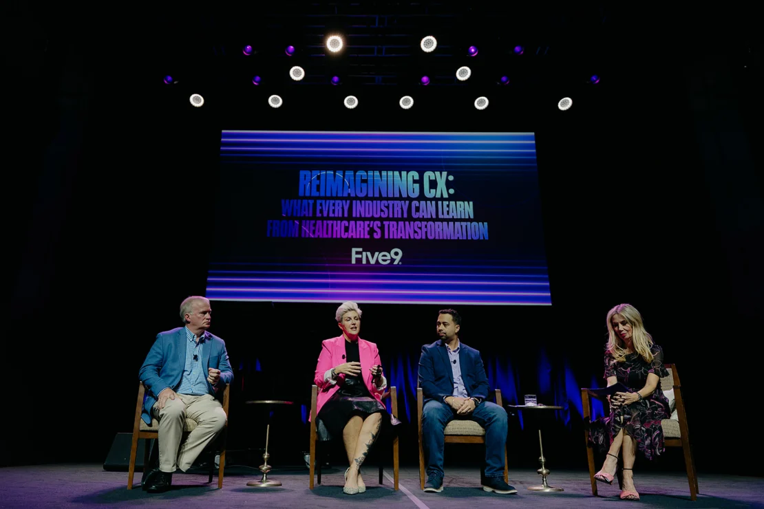 Four panelists sit on stage under a screen displaying "Reimagining CX: What Every Industry Can Learn From Healthcare’s Transformation, Five9.