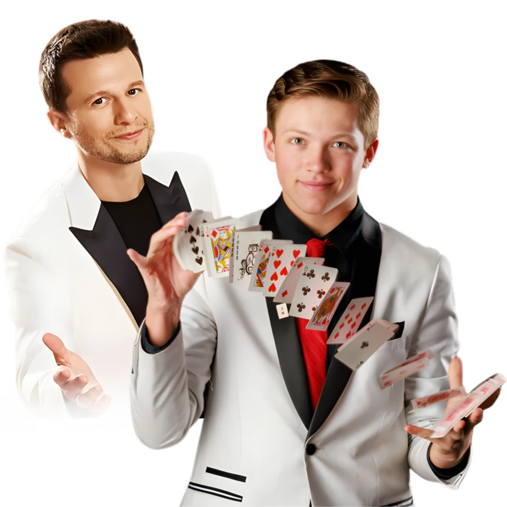 Two men in white tuxedos; one is holding out his hands, while the other is performing a card flourish, fanning playing cards through the air.