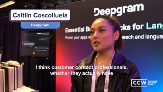 A woman wearing a black jacket speaks at a Deepgram booth during Customer Contact Week, with subtitles displaying her comments on customer contact professionals.
