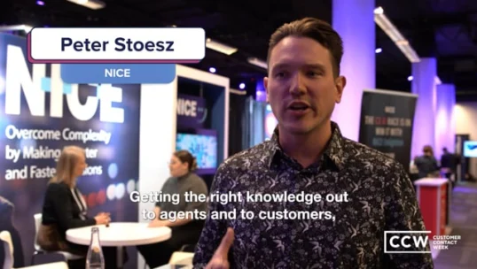 A man stands in a convention hall near an exhibit booth with a NICE sign, speaking about sharing knowledge with agents and customers. A CCW Customer Contact Week logo is displayed on screen.